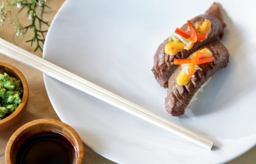 Go on a Food Adventure - beef nigiri with wasabi and soy sauce at the side served on a white plate with wooden chopsticks